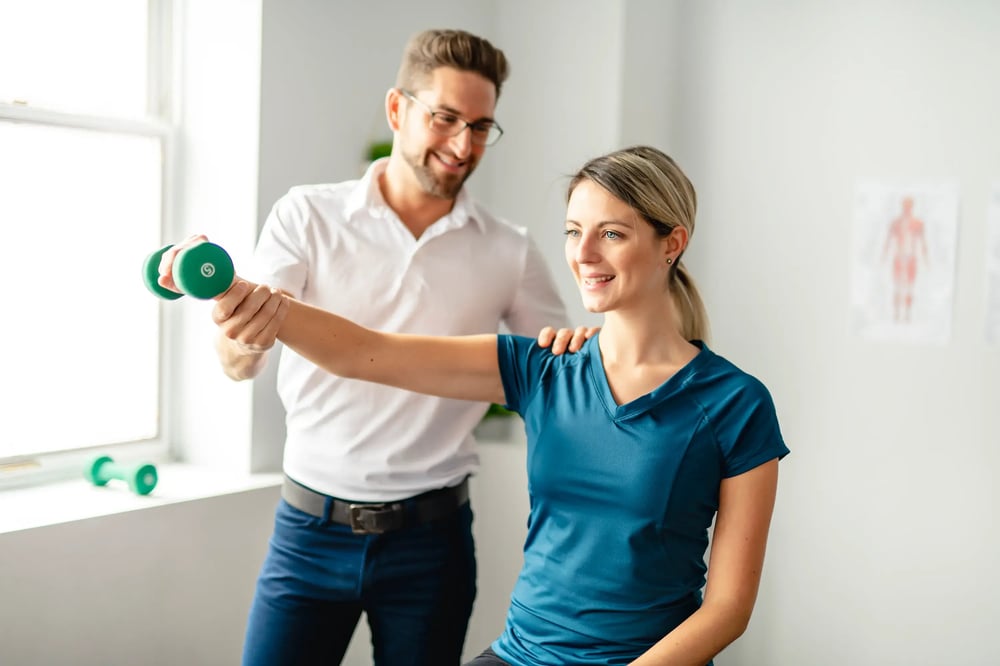 man guiding a woman with raising a dumbbell